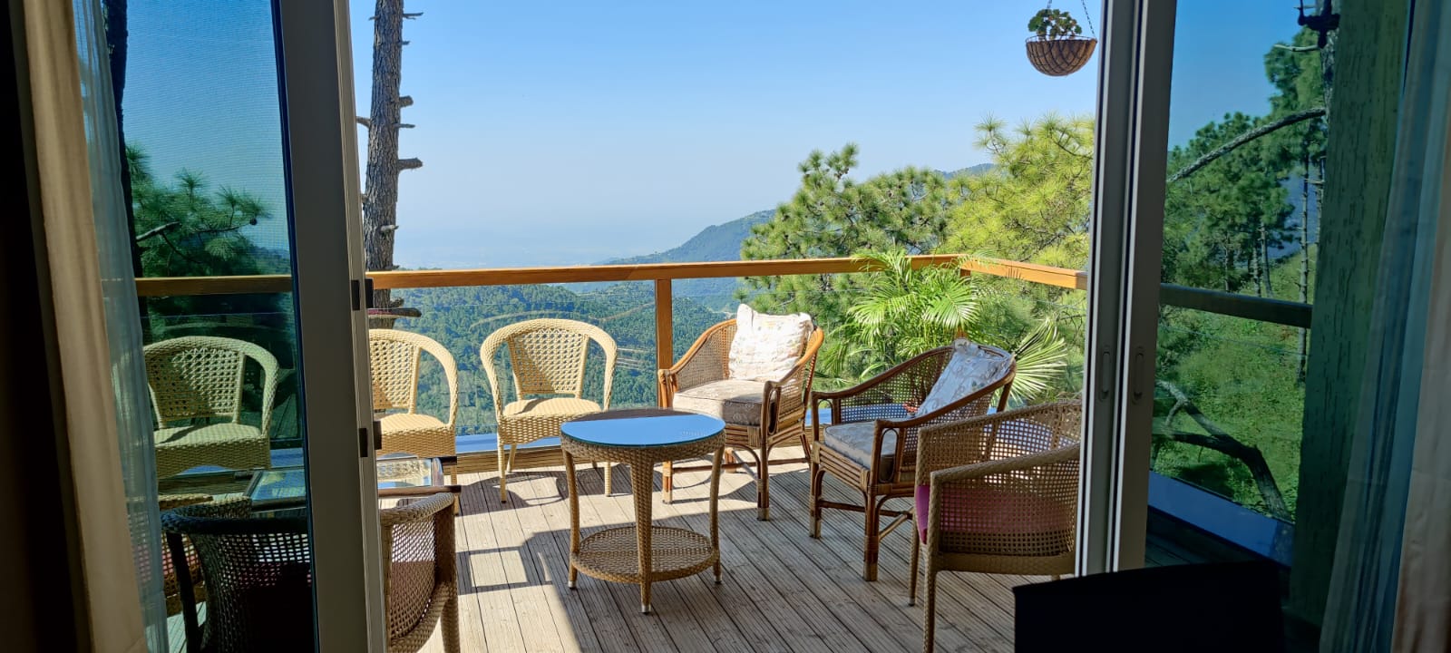 Private balcony with cane seating overlooking pine ridges